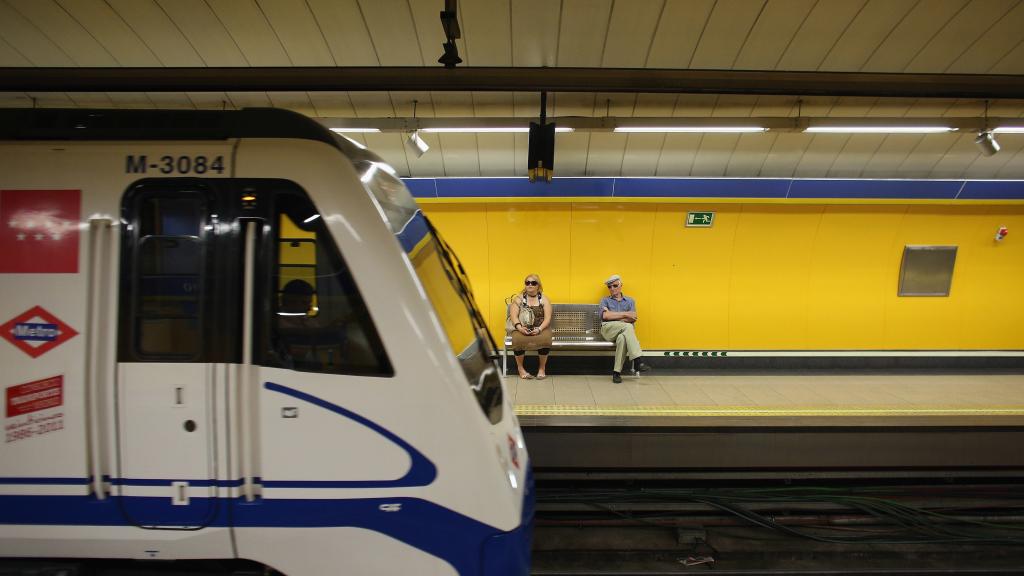 Dos pasajeros esperan al metro en una estación madrileña.