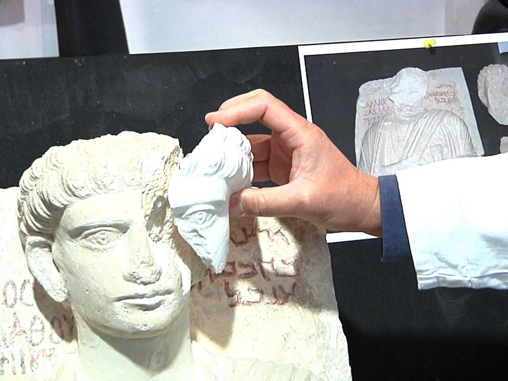 Uno de los arqueólogos muestra la reparación de uno de los dos relieves.