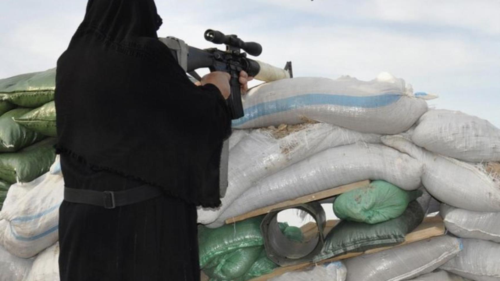 Una mujer dispara desde una trinchera.