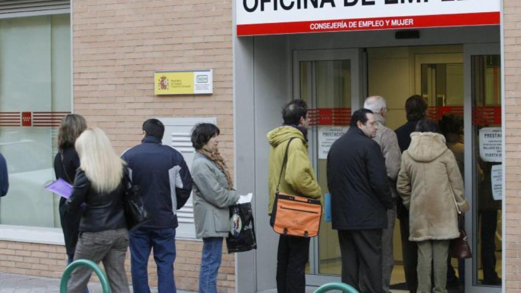 Un grupo de personas que hacen cola en la entrada de una oficina de empleo.
