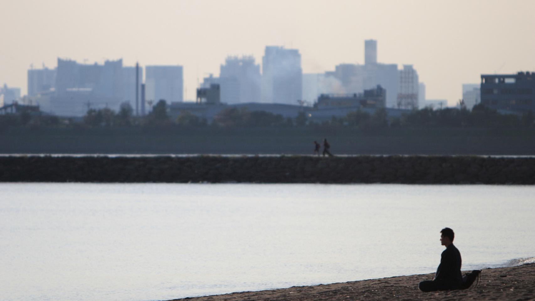 Una persona medita mirando al agua.