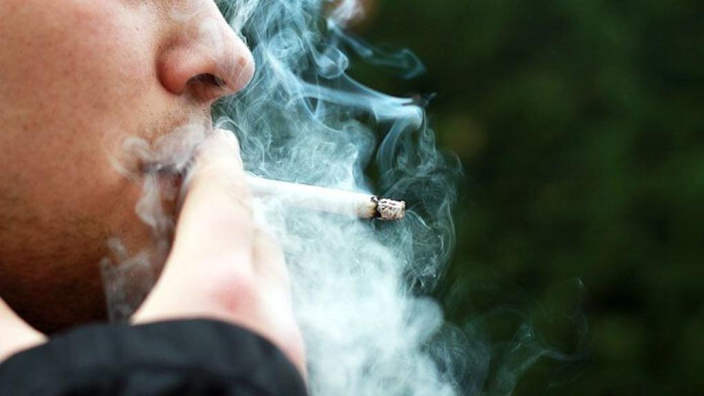 Un hombre fuma un cigarrillo.