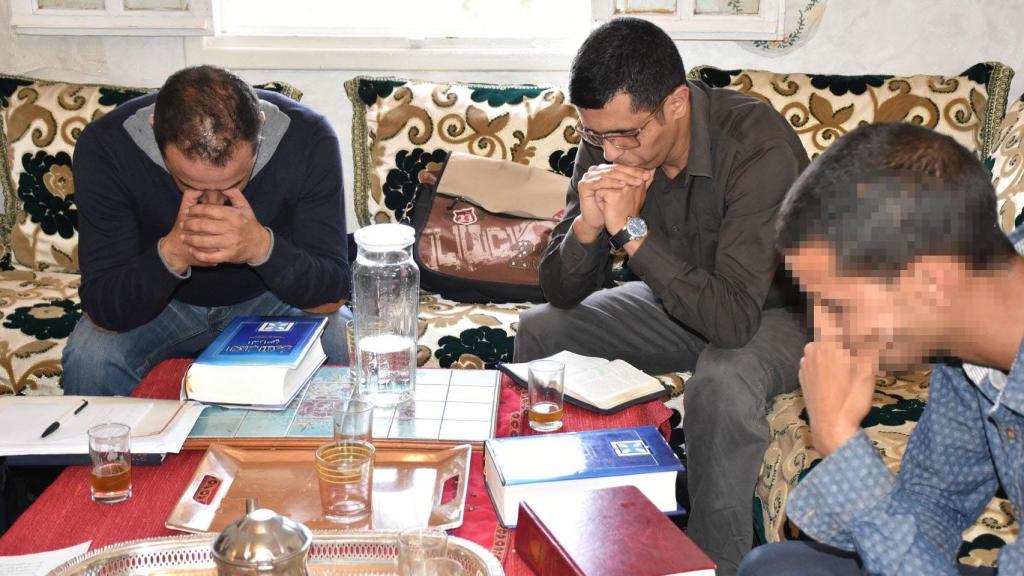 Las biblias en árabe descansan sobre la mesa mientras los conversos rezan.