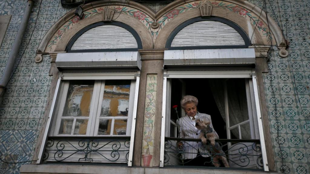 Una mujer junto a su mascota, en un balcón de Lisboa