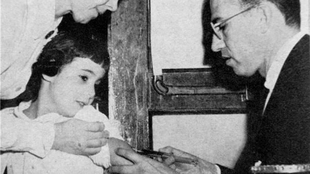 Jonas Salk vacunando a una niña.
