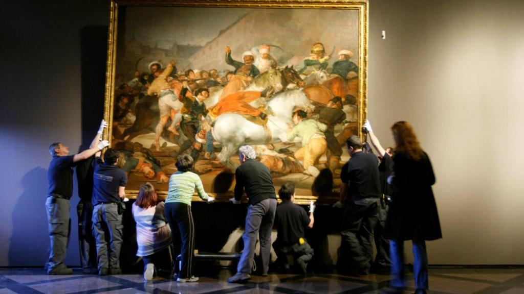 Empleados del Prado cuelgan la Carga de los mamelucos, tras ser restaurado.
