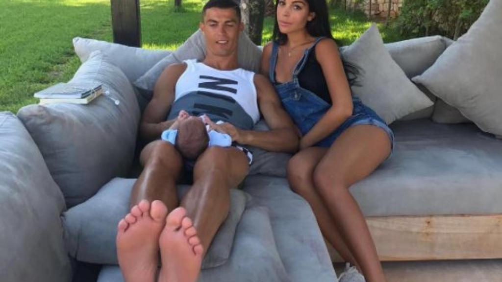 Cristiano sostiene a uno de sus mellizos entre sus piernas, junto a Georgina.