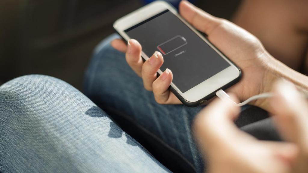 Una joven trata de cargar la batería agotada de su teléfono móvil.
