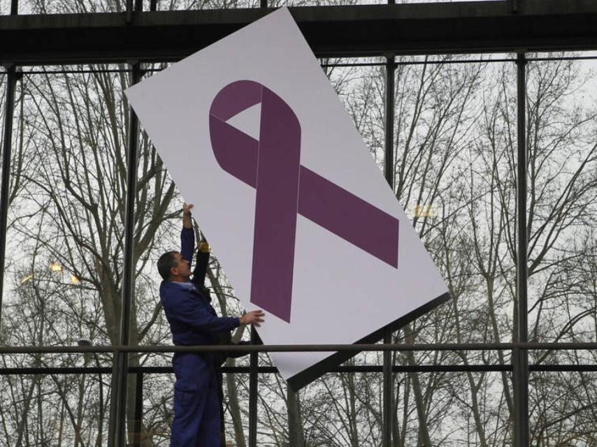 Un trabajador coloca un crespón morado en referencia a la violencia de género