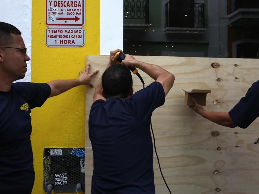 Unos hombres cubren la entrada de un local con tablas de madera.
