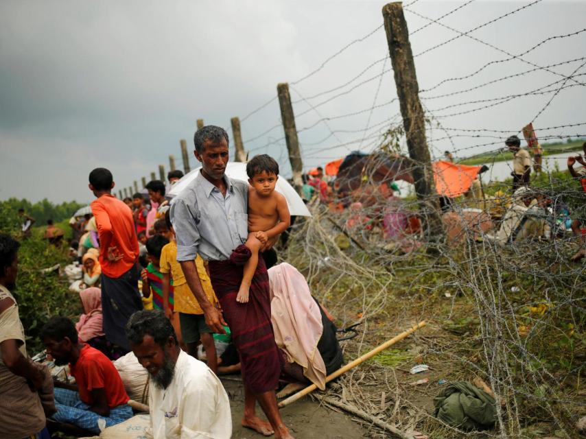 Un hombre camina a lo largo de una cerca de alambre de púas en Maungdaw, Myanmar