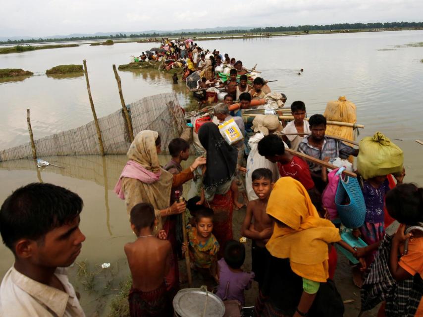 Los refugiados esperan a que el barco cruce un canal después de cruzar la frontera a través del río Naf en Teknaf