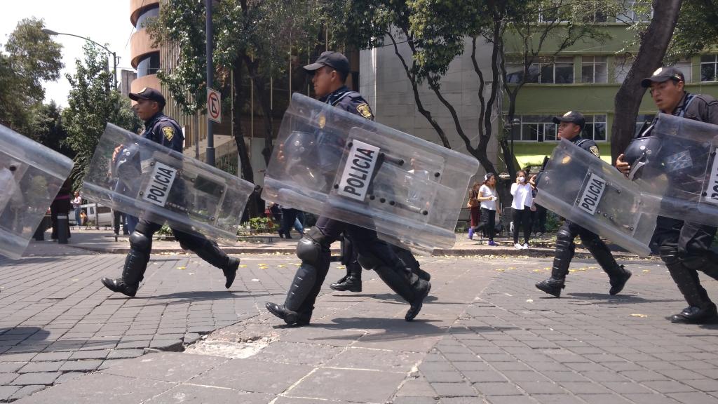 Policías con escudos para protegerse de los derrumbes.