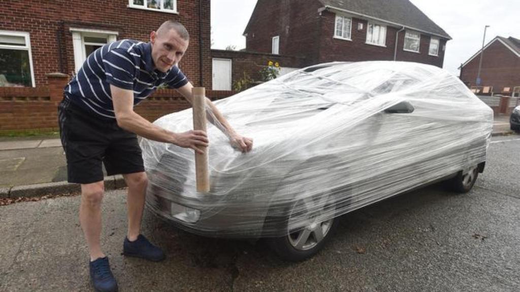 Neil Junglas envolviendo el coche delante de su casa