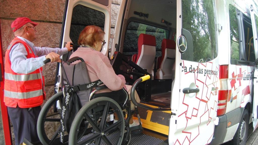 Un voluntario de Cruz Roja ayuda a subir a una usuaria al vehículo.