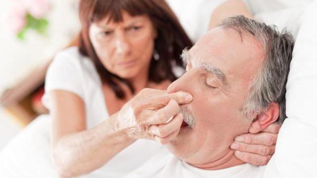 Una mujer tapa la nariz a su marido para que no ronque.