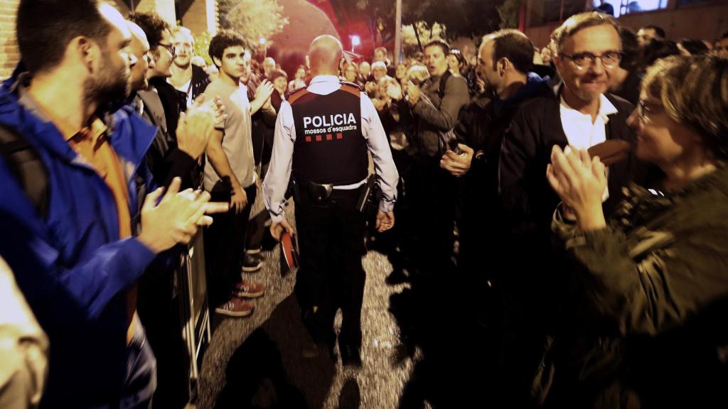 Un agente de los Mossos es despedido entre aplausos por una multitud independentista.