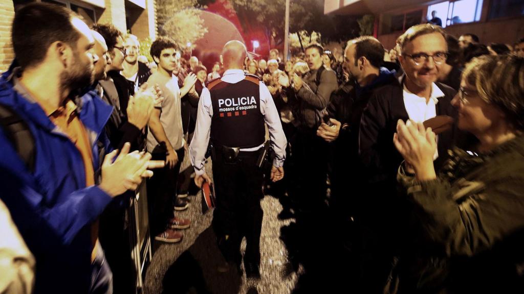 Un agente de los Mossos es despedido entre aplausos por una multitud independentista.