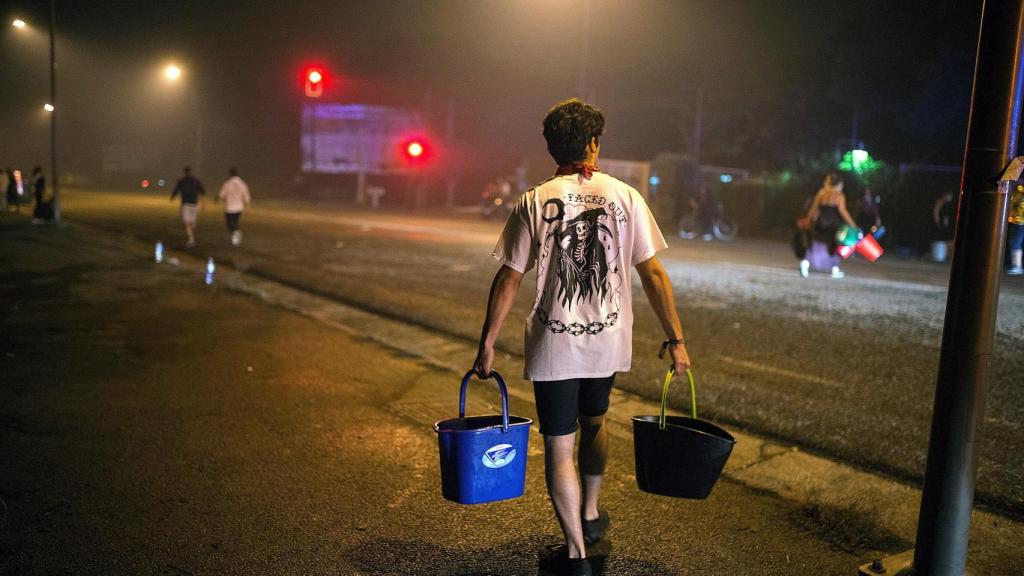 Un vecino acarreando calderos de agua para apagar un incendio en el centro de Vigo.