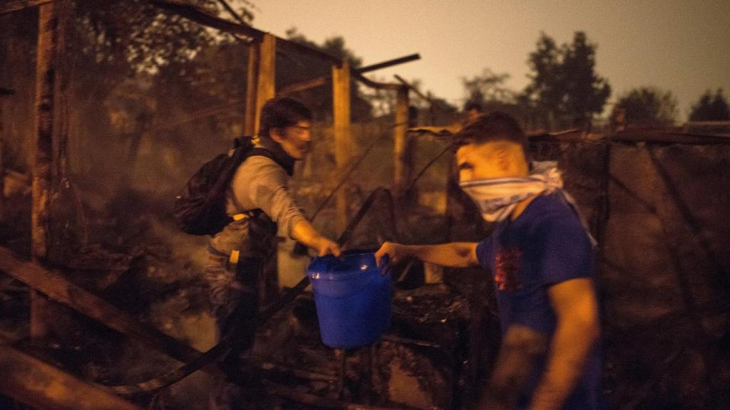 Voluntarios apagando llamas y protegiéndose del fuego en Vigo.