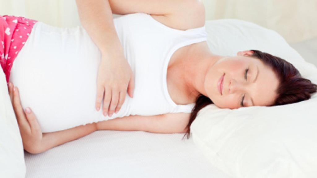 Una mujer embarazada durmiendo de lado.