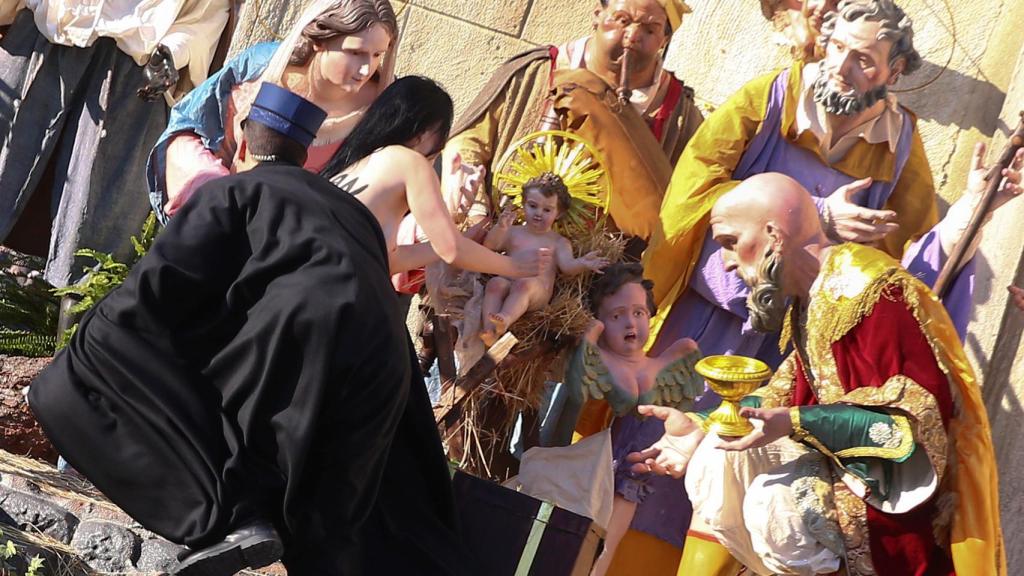 La activista de Femen intentando coger al niño.