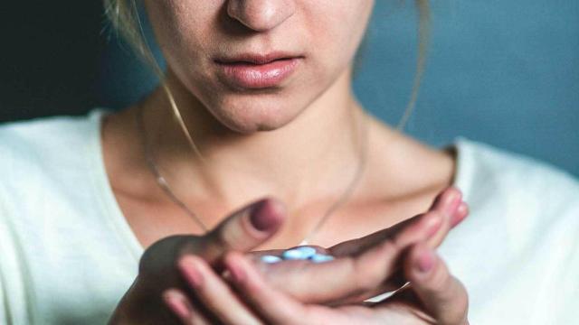 Una mujer tomándose una pastilla.