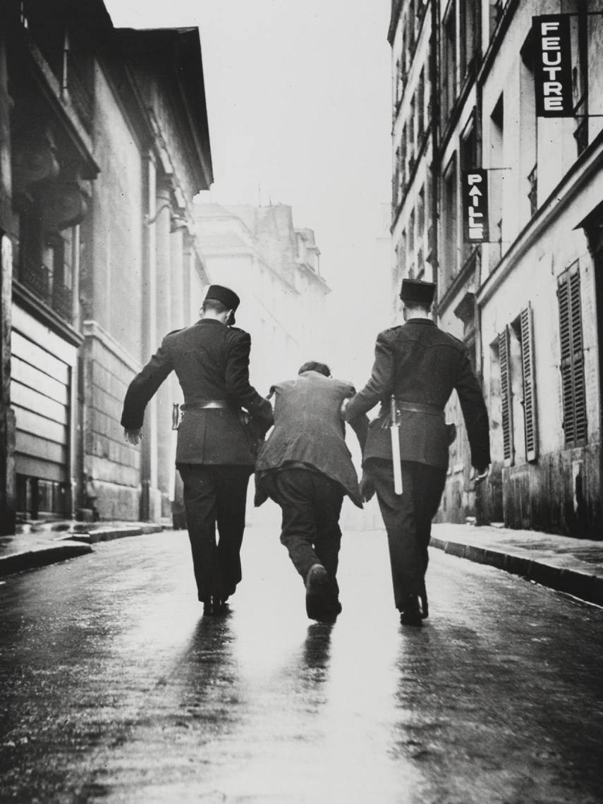 Dos policías se llevan a un crochard borracho.