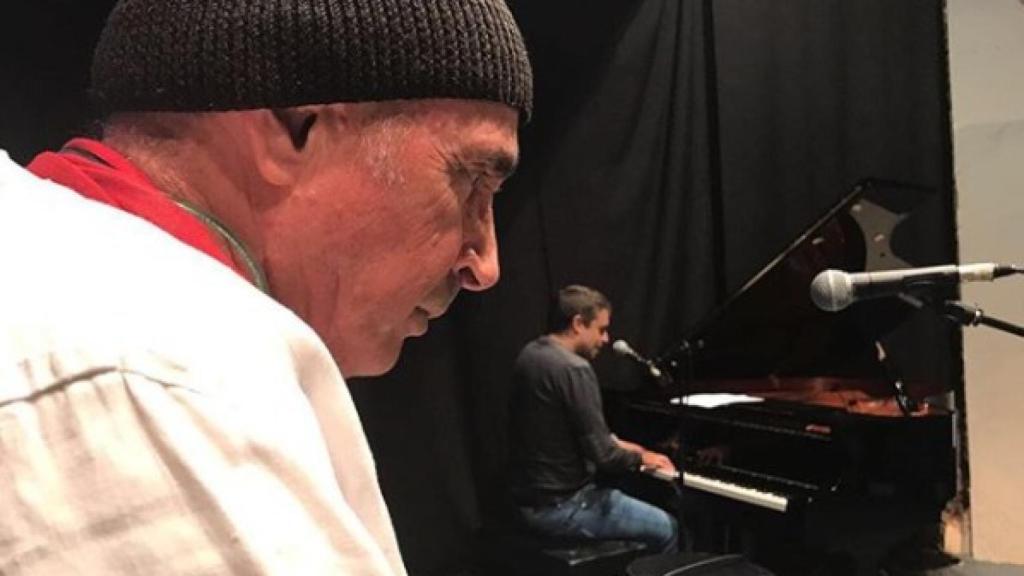 Guix toca el piano ante la mirada de Lluís Llach.