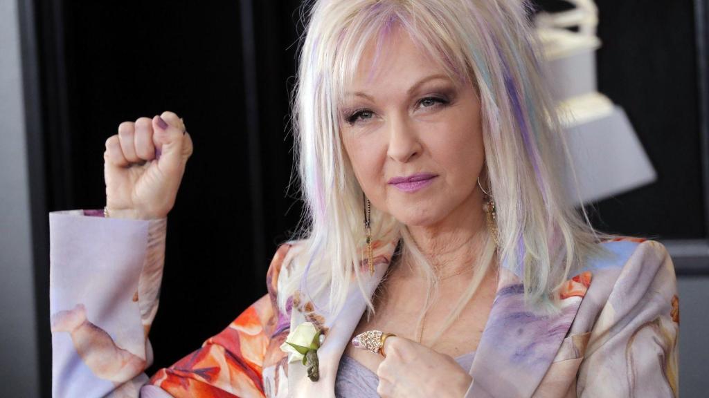Cindy Lauper levanta el puño en la alfombra roja.