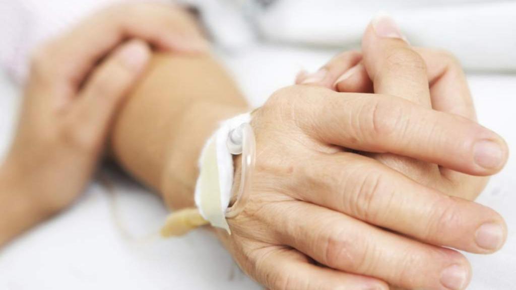 Una persona posa su brazo sobre un enfermo que se encuentra ingresado.