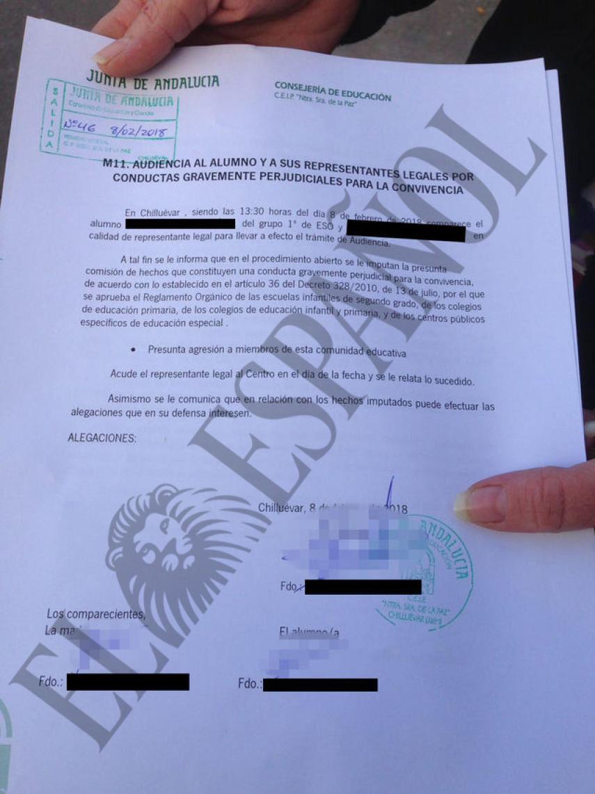 La madre de uno de los niños acusados muestra el acta de expulsión