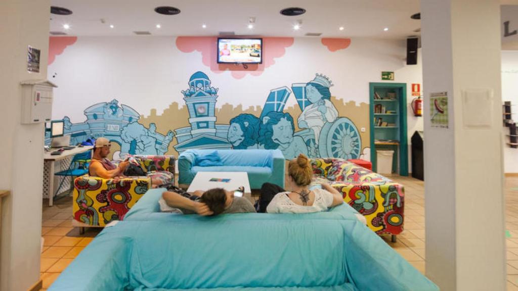 Varios turistas descansan en la sala común de un hostel.