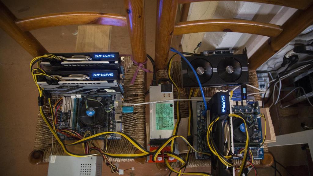 Varios equipos de minado de criptomonedas sobre dos sillas de nea en un domicilio de Sevilla.