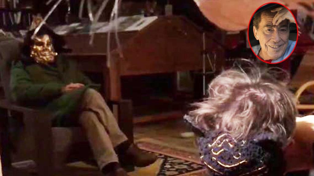 Fotograma original de la primeraa película porno de Sánchez Dragó. A la izquierda, Dragó sentado en una butaca en plena actuación, se cubre el rostro con una máscara carnavalesca.