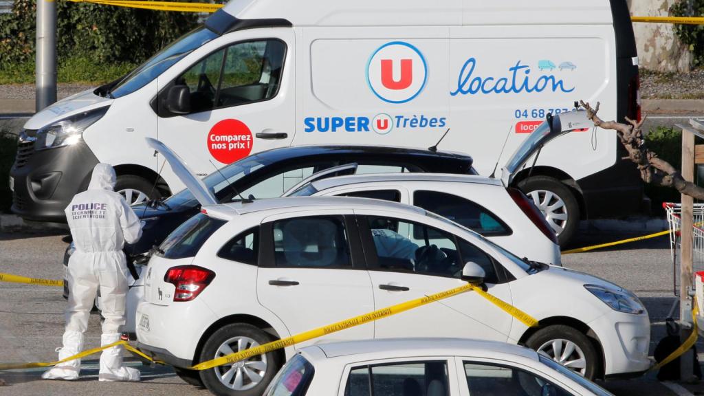 La Policía científica examina uno de los coches junto al supermercado atacado