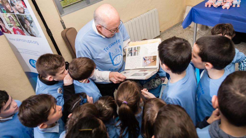 Gerardo Prieto mira un álbum con fotos de sus pacientes rodeado de niños.