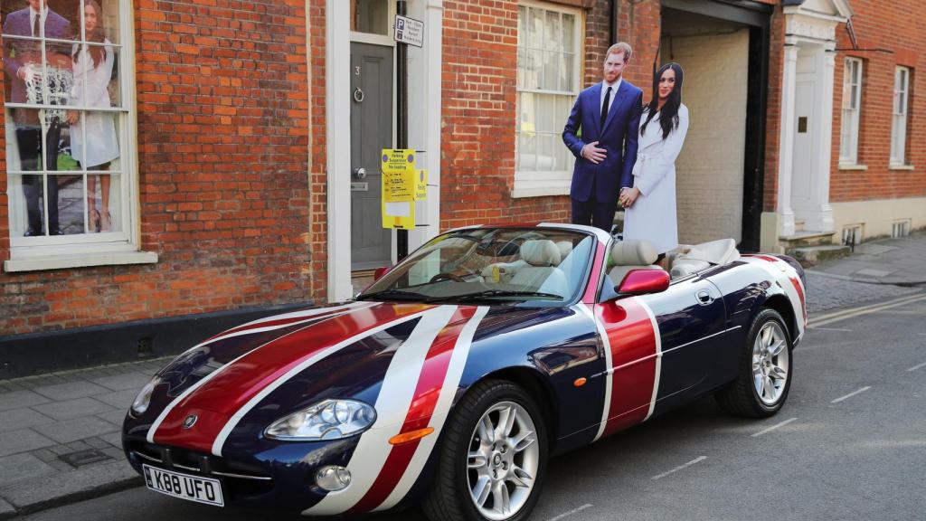 Un jaguar se pasea por la ciudad londinense con dos figuras de Harry y Meghan.