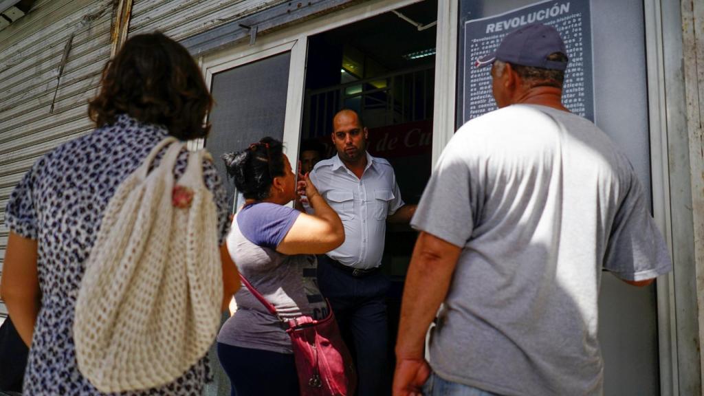 Algunos clientes preguntando por información a un empleado de Cubana.