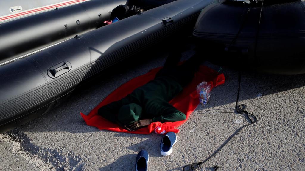 Un inmigrante duerme entre dos lanchas neumáticas en el puerto de Tarifa.