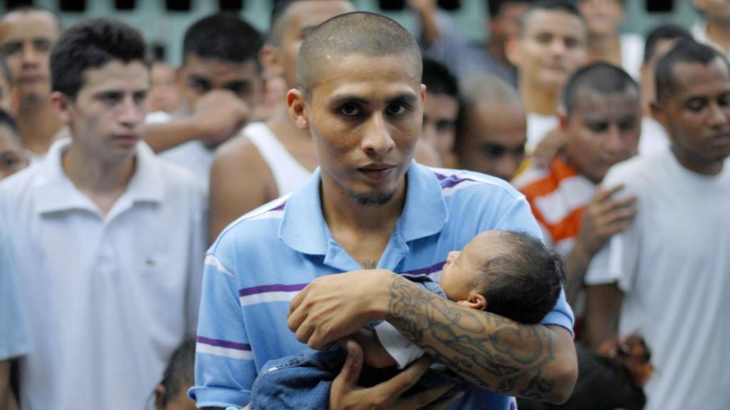 Un pandillero sujetando a un bebé.