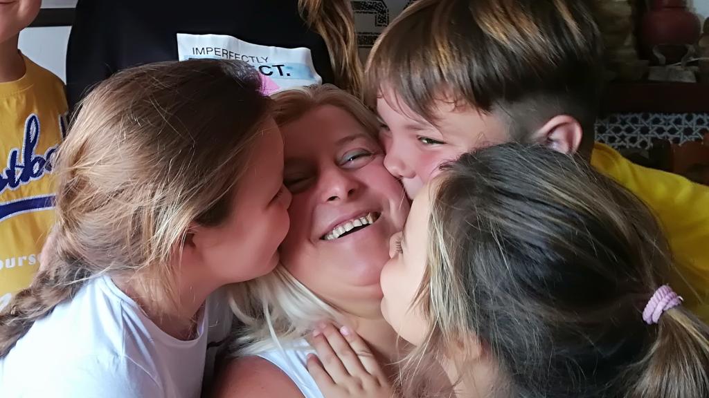 Paqui recibe el beso de tres de sus nietos.