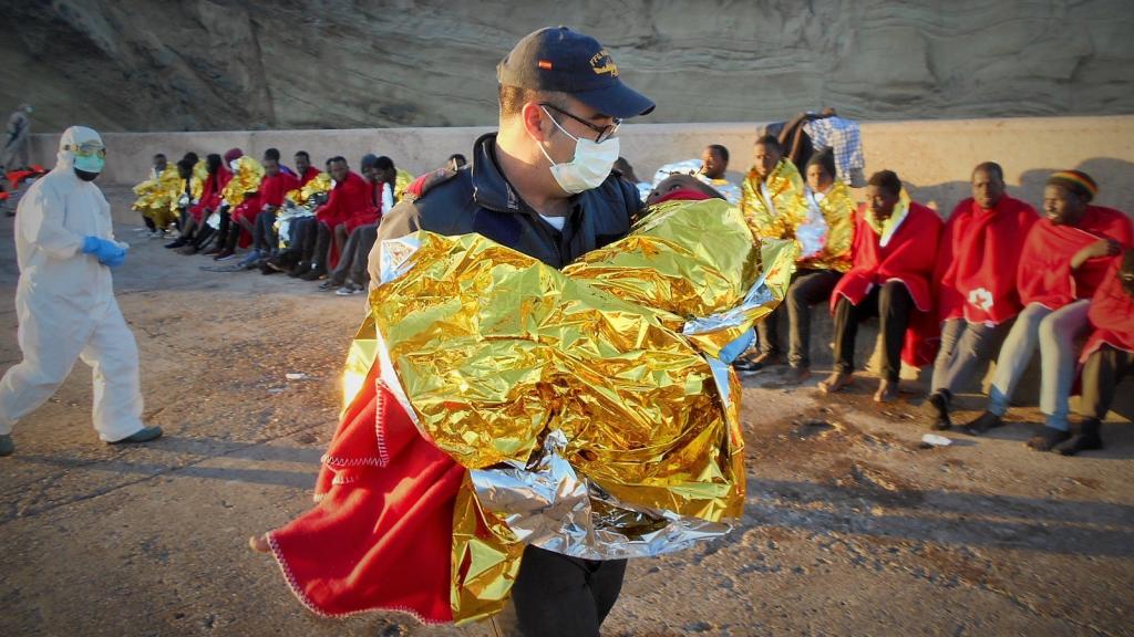 Un efectivo de la Armada atiende a un niño a su llegada a la isla de Alborán.
