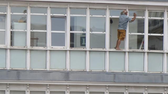 El hombre limpiando los cristales de manera muy imprudente.
