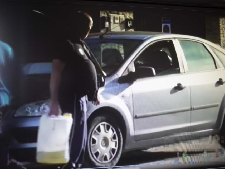 Un detective que siguió a este hombre durante varios días logró demostrar que trabajaba en un taller de coches como mecánico. En la imagen se le ve cargando con una garrafa de aceite delante del motor de un coche averiado.