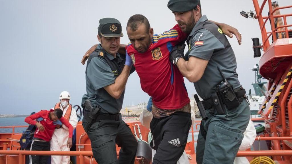 Dos agentes de la Guardia Civil atienden a un inmigrante que viajaba en una patera por las aguas del Estrecho.