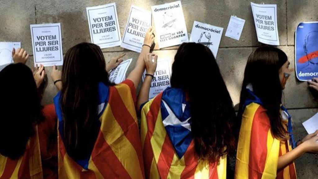 Varias menores cuelgan carteles llamando a votar durante el 1-O