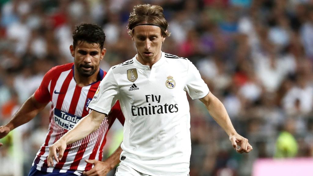 El centrocampista croata del Real Madrid, Luka Modric, conduce el balón ante el delantero hispano-brasileño del Atlético de Madrid, Diego Costa