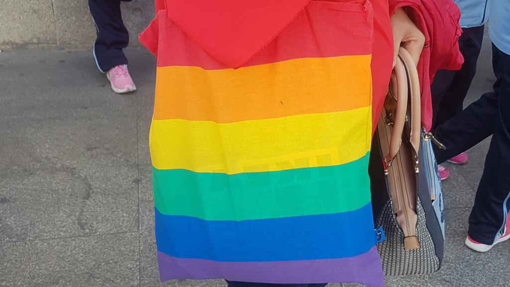Una señora vestida con bolso de la bandera del Orgullo Gay.