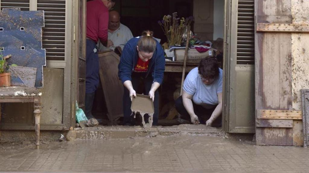 Dos vecinas tratan de achicar el agua.